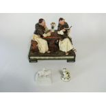 A late 19th century German ceramic group of a pair of monks reading at a table raised on a