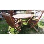 A teakwood garden table of octagonal form together with four folding teak armchairs