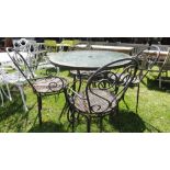 A circular café table with plate glass top and four matching chairs