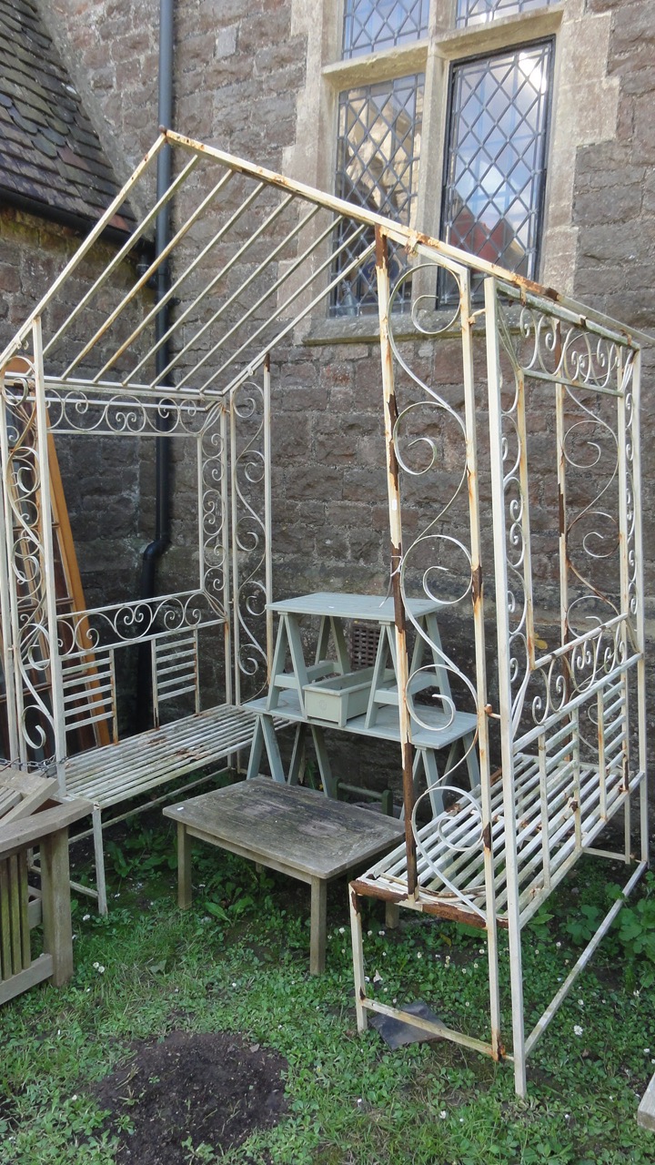 A gazebo with decorative scroll worked finish enclosing two simple benches