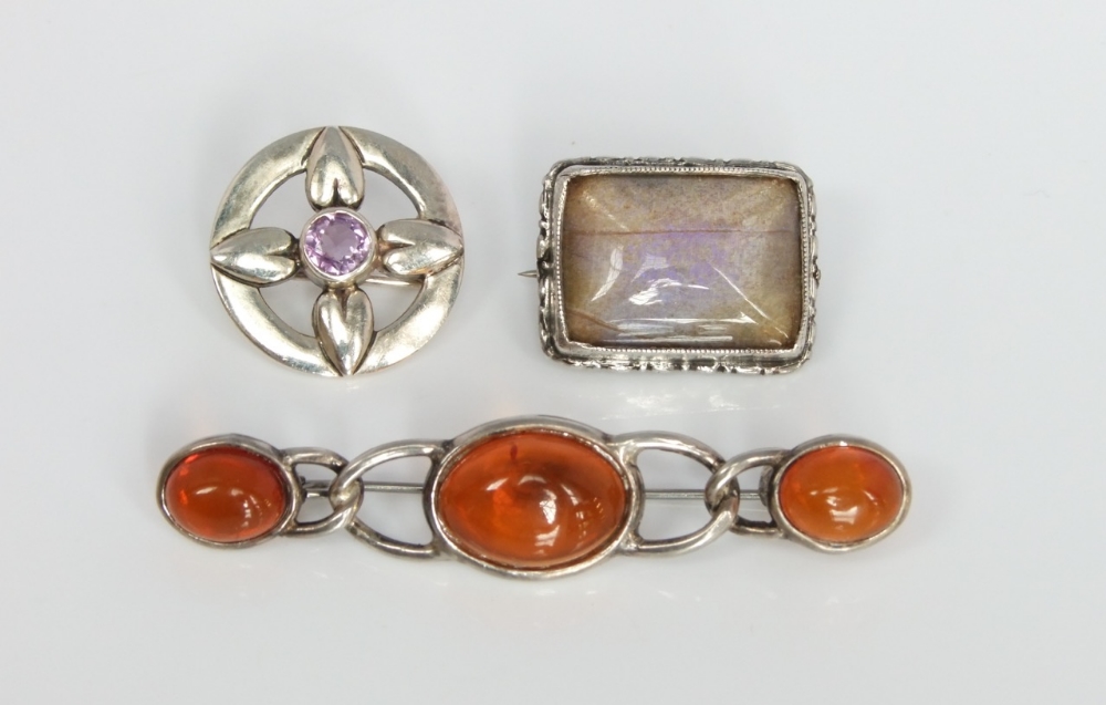 Three pieces of Scottish silver jewellery to include a small circular brooch, an amber set bar