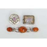 Three pieces of Scottish silver jewellery to include a small circular brooch, an amber set bar