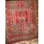 A Persian floor rug decorated with architectural panels upon a red ground, 200cm x 105cm