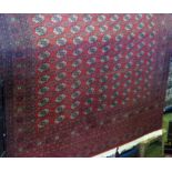 A large Bokhara floor rug decorated with various geometric medallions upon a red ground, 380cm x