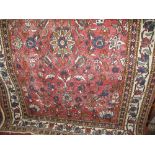 A Persian type floor rug centrally decorated with scrolled foliage upon a red ground, 210cm x 160cm