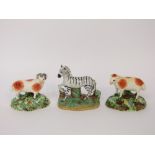 A 19th century Staffordshire model of a zebra together with a pair of 19th century Staffordshire