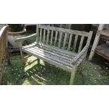 A weathered teak two seat garden bench with slatted seat and back (AF).