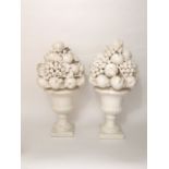 A pair of large white glazed table centrepieces modelled as urns containing fruits including