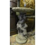 A weathered contemporary cast composition stone bird bath, the pedestal in the form of a cherub with