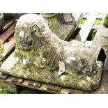 A weathered cast composition stone garden ornament in the form of a recumbent lion raised on a