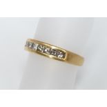 An ladies 18ct gold and diamond ring, channel set with seven square cut diamonds, 3.7g, ring size J