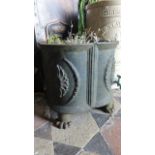 A small cast iron planter of squat quatrefoil form with foliate detail and paw feet.