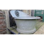 A vintage galvanised hip bath, later converted to a water feature with applied lions mask spout