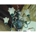 An attractive green wrought metal five branch ceiling light with frosted glass shades and floral