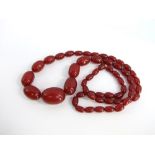 A string of synthetic oval cherry amber style beads, largest bead 3cm by 2cm. Length 36cm