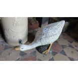 A contemporary cast composition stone garden ornament in the form of a goose with painted finish.