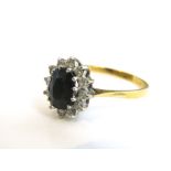 An 18k gold sapphire and diamond ladies cluster ring, central dark blue sapphire (8 x 6mm) with a