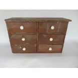 Victorian stained pine bank of six specimen drawers, each with ceramic handles, 33cm high by 51cm