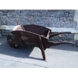 A vintage stained elm wheel barrow with iron rim