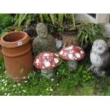 A pair of painted and weathered toadstools, an owl upon a log and a terracotta chimney pot.