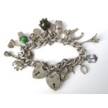 A sterling silver curb link charm bracelet set with numerous silver charms and some unmarked white
