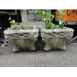 A pair of weathered composition stone garden planters of square squat form with shaped outline and