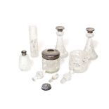 A pair of cut glass perfume bottles with flared bases and silver collars and four other pieces