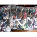 Three large sealed bags of costume jewellery.