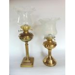 Two brass oil lamps with Vaseline type glass shades and glass flues both stood on Corinthian type