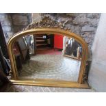 A Victorian style gilt framed overmantle mirror of arched form with a moulded frame with scrolling