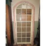 A reclaimed pine framed casement window of arched form with segmented rectangular glazed panels
