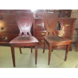 A pair of Victorian mahogany hall chairs with shield shaped backs raised on square tapered supports