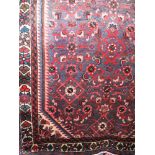 A Persian floor rug decorated with red scrolled foliate upon a blue ground, 200 x 95 cm approx