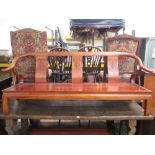 A substantial Chinese hardwood bench, the shaped splat back with carved geometric detail and set