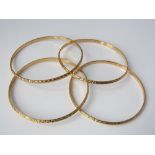 A set of four 21ct gold bangles with bright cut decoration, 46g