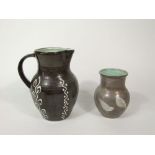 A Fishley Holland pottery jug with stylised leaf, wavy line and dot detail in white slip on a dark