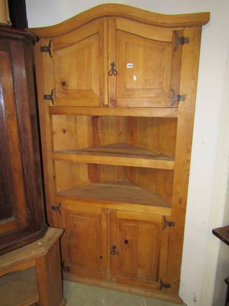 A stripped pine two sectional corner cupboard of full height, partially enclosed by panelled doors