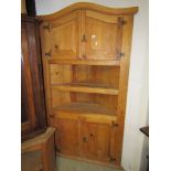 A stripped pine two sectional corner cupboard of full height, partially enclosed by panelled doors