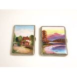 A pair of white metal cigarette cases with applied enamel fronts of landscapes scenes (2)