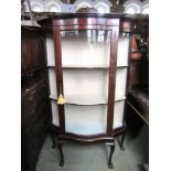 An Edwardian mahogany display cabinet of full height enclosed by a glass serpentine moulded door and