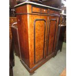 A 19th century walnut and ebonised side cupboard enclosed by two panelled doors and two frieze