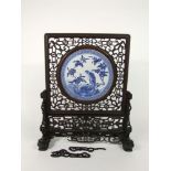 A Chinese table screen with inset circular blue and white painted plaque in the Kangxi manner with