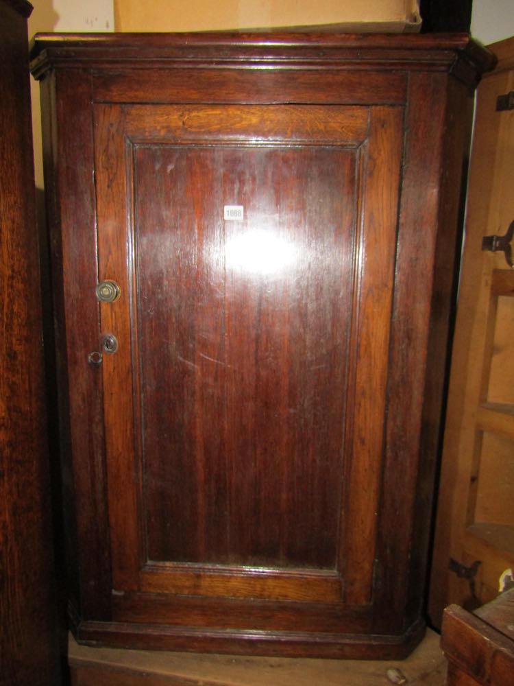 Georgian oak country made hanging corner cupboard enclosed by a single panelled door with shaped