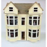 A double bow fronted dolls house fitted with a collection of furniture, painted in cream, 61 cm high