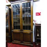 An Edwardian oak bookcase of full height enclosed by four doors, two with leaded light panels