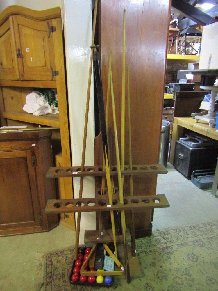 A cue rack, a number of snooker cues, balls, triangle, brush, etc