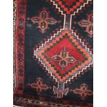 A Persian floor rug decorated with multi-coloured geometric medallions upon a deep navy blue ground,