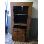 A rustic vintage floorstanding side cupboard, partially enclosed by a ledge and brace door with