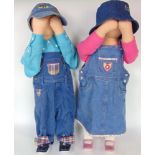 A pair of Tantrum Tots dolls, clothed with hands to their faces, 80 cm high (2)