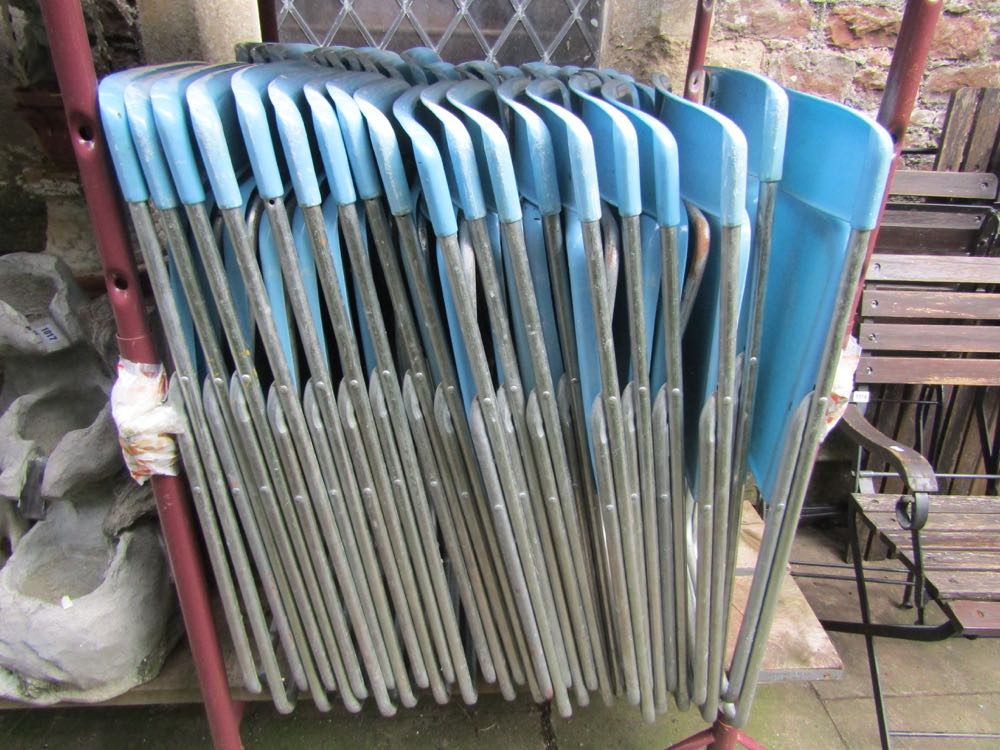 Thirty nine folding pop chairs with light blue coloured moulded plastic seats and back rails